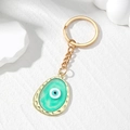 Detailweergave van evil eye sleutelhanger met blauwe hars en gouden legering - Groen Ovaal Oog