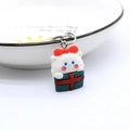 Detail of cartoon cat in a Christmas gift box resin keychain charm on a white bowl - Cat in Gift Box