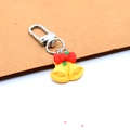 Detailed view of yellow Christmas bell keychain with red bow and green holly leaf charms - Bell
