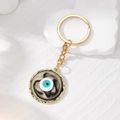 Detailed macro view of the gold-plated evil eye keychain with marble texture background - Black Round