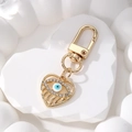 Dettaglio portachiavi a cuore malocchio dorato con zirconi su base in pietra bianca - Cuore Occhio Bianco / Bianco
