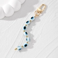 Dettaglio portachiavi malocchio con perline ovali in resina blu e chiusura dorata - Perline Ovali Bianche