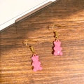 Close-up of pink resin gummy bear earrings with golden metal hooks on wood background - Pink Bear