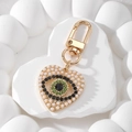 Detail eines Herz-Anhänger mit bösem Auge, weißen Perlen und goldenem Karabiner - Perle Herz