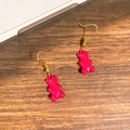 Detail of rose red gummy bear earrings with golden hooks on wooden background - Rose Red Bear