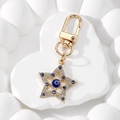 Detailed macro view of golden star Evil Eye keychain with sparkling blue rhinestones - Sapphire Blue