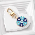 Detailed close-up of blue floral evil eye keychain with gold lobster clasp on white stone - Heart Flower