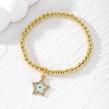 Macro view of gold beaded bracelet featuring a star-shaped evil eye charm and crystal accents - White Eye Star