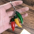 Dettaglio del portachiavi con peperoncini in resina rosso giallo e verde in mano - Peperoncino Colorato