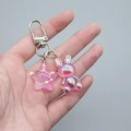 Detailed macro view of iridescent resin rabbit charm and glitter star on metal keychain - Transparent Rose Red