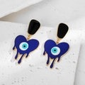 Vue macro détaillée des boucles d'oreilles cœur œil maléfique en émail sur pierre - Or Coeur