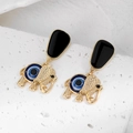 Détail de boucles d'oreilles éléphant dorées avec perles œil bleu sur pierre blanche - Éléphant Doré