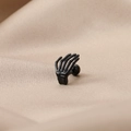Vista macro de un pendiente punk de acero inoxidable negro con forma de mano de esqueleto - Mano de esqueleto negra