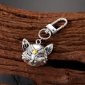 Close-up of silver metal fox keychain with moon detail and yellow gemstone on wood - Cat Head Style