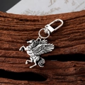 Vintage silver Pegasus metal keychain with detailed wings on a rustic wooden surface - Pegasus Style