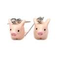 Detalle de pendientes de cerdo rosa hechos de resina con ganchos plateados en fondo blanco - Cerdo