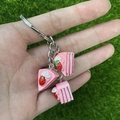Detailweergave van de roze aardbeientaart sleutelhanger met miniatuurgebakjes van hars - Roze aardbeientaart