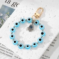 Blue evil eye beaded keychain with silver hamsa hand pendant on a white stone background - Sky Blue Eye Hamsa Hand