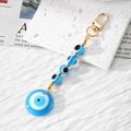 Handmade Evil Eye keychain with blue resin pendant and golden clasp on a textured background - Sky Blue