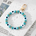 Handmade Evil Eye beaded keychain with turquoise and gold accents on a stone background - Turquoise Eye