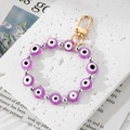 Detailed macro view of purple Evil Eye beads with golden lobster clasp on a stone surface - Purple Eye