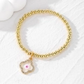 Golden beaded elastic bracelet featuring a clover charm with a pink evil eye and zircons - Four-leaf Clover / Pink Eye Flower