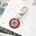 Macro shot of evil eye keychain with red and blue crystals on a textured stone surface - Silver/Red Zirconia