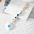Handmade Evil Eye keychain with blue resin beads and golden clasp on stone board - White