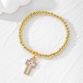 Golden beaded bracelet with a sparkling rhinestone cross pendant and pink evil eye charm - Pink Eye Cross