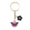 Detailed view of pink butterfly and blue flower charms on a golden metal keychain - Round Butterfly And Black Sakura