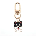 Dettaglio di un portachiavi smaltato Shiba Inu nero con moschettone dorato su sfondo bianco - Husky