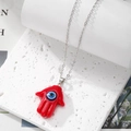Macro shot of silver chain with red Hamsa Hand and Evil Eye resin pendant - Red