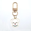 Détail d'un porte-clés chien blanc mignon en alliage doré avec finition émaillée - Chiot Blanc