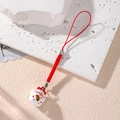 Macro shot of Japanese Maneki Neko lucky cat pendant with red woven cord on stone - Red