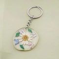 Detailed close-up of a resin keychain with a white daisy flower and colorful butterflies - White Daisy