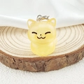 Detalle de un lindo colgante de gato de resina amarilla translúcida en base de madera - Amarillo gelatina