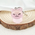 Primer plano de un llavero de gatito rosa translúcido hecho de resina mate en madera - Rosa Gelatina
