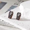 Macro shot of coffin-shaped wooden stud earrings with skull and skeleton bone patterns - Skull Coffin