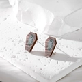 Detail of wooden coffin earrings with owl pattern on minimalist stone display - Owl Coffin