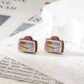 Gros plan de boucles d'oreilles créatives en bois en forme de sac aux rayures arc-en-ciel - Stylos aquarelles