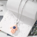 Pink Hamsa hand necklace with blue evil eye pendant on a fine silver-tone metal chain - Light Pink