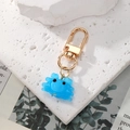 Détail d'un porte-clés crabe en résine bleue avec fermoir mousqueton doré sur pierre - Bleu Translucide