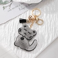 Gros plan d'un porte-clés chat en strass étincelants avec pompon noir et métal doré - Chat Noir Avec Cloche Noire