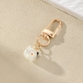Detail eines süßen Katzen-Schlüsselanhängers aus weißem Harz mit goldenem Karabiner - Katze