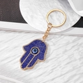 Gouden Hamsa Hand sleutelhanger met blauw boze oog en fonkelende kristallen erop - Koningsblauw Gouden Hand