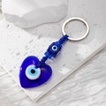 Blue heart evil eye glass keychain with woven rope on a textured stone surface - Royal Blue Heart
