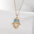 Golden Hamsa Hand necklace with blue opal and white cubic zirconia on a white pedestal - Hamsa Hand (Stainless Steel Chain)