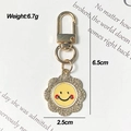 Dettaglio del portachiavi girasole con strass brillanti e ciondolo sorriso in smalto - Sole
