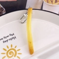 Detailaufnahme eines kreativen Wellen-Pommes-Schlüsselanhängers auf einem Keramikteller - Einzelne Pommes Frites