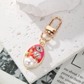 Vintage gold-plated oval keychain with pink enamel, crystals, and faux pearl on a stone slab - Rose Pink Pearl